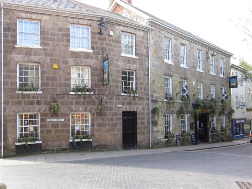 een groot bakstenen gebouw met ramen aan een straat bij White Hart Hotel in St Austell