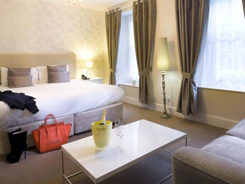 a hotel room with a bed, desk, chair and a lamp at White Hart Hotel in St Austell