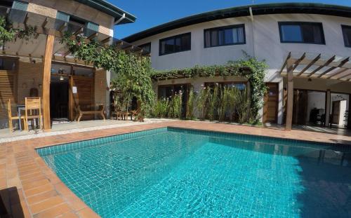 a swimming pool in front of a house at Nai'a Suites in Ubatuba