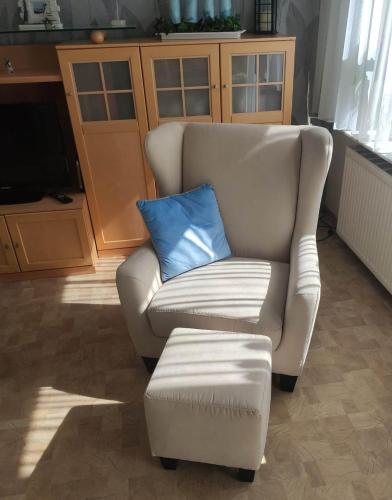 a white chair with a blue pillow and a stool at Ferienhaus Emden Zur Mühle Nordseeküste in Emden