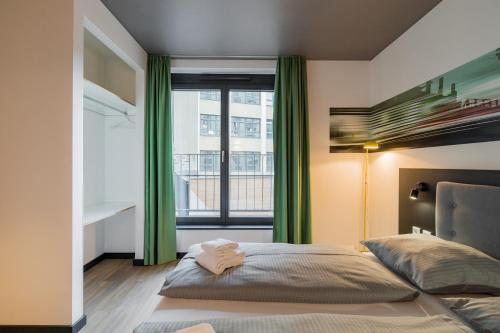 a bedroom with a bed with green curtains and a window at Nena Apartments - Kreuzberg 61 in Berlin