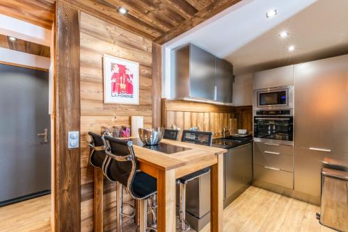 Eine Küche mit Holzwänden und eine Bar mit Hockern in der Unterkunft Flocon des Neiges in Praz-sur-Arly