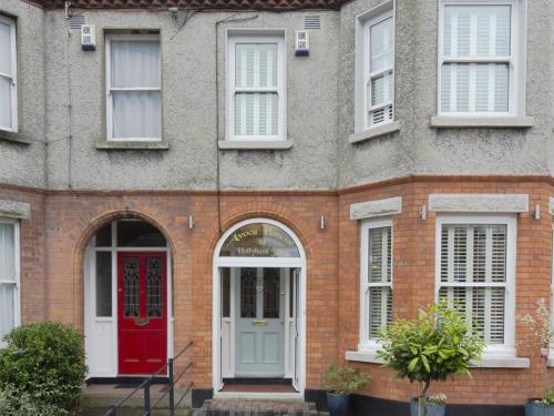 un edificio de ladrillo con puerta roja y ventanas blancas en Avoca House B&B en Dublín