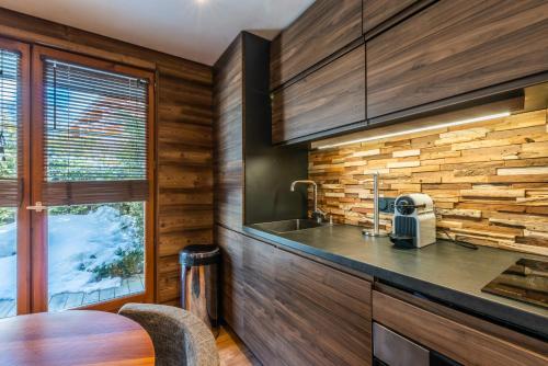 une cuisine avec un comptoir, un évier et une fenêtre dans l'établissement Le Hameau des Neiges, à Praz-sur-Arly