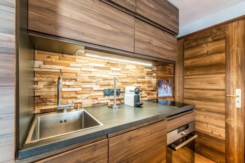 - une cuisine avec un évier et un mur en bois dans l'établissement Le Hameau des Neiges, à Praz-sur-Arly