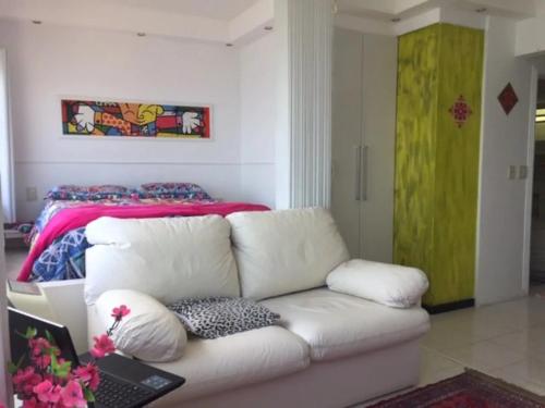 a living room with a white couch and a bed at Ilha Porchat - Loft Vista Incrível in São Vicente