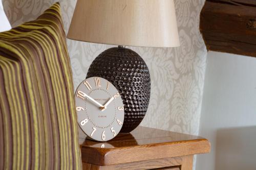 a clock sitting on a table next to a lamp at Broom Hall Inn in Stratford-upon-Avon