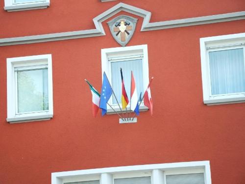 een rood gebouw met verschillende internationale vlaggen erop bij Hotel Ulmer Stuben in Ulm