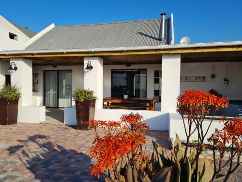 a white house with red plants in front of it at Oorgenoeg in Langebaan in Langebaan
