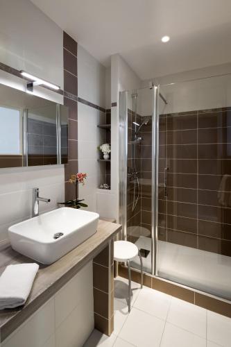 a bathroom with a sink and a shower at Hôtel Les Nations The Originals Boutique VICHY in Vichy