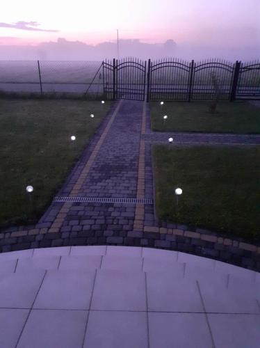 a brick walkway leading to the ocean at sunset at Domek mamy in Tykocin