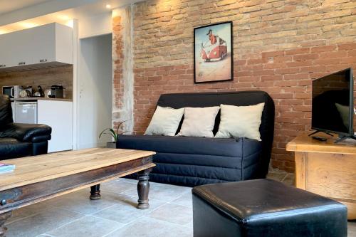 a living room with a couch and a brick wall at #M0 Le charme voironnais T3 6 persons City center in Voiron