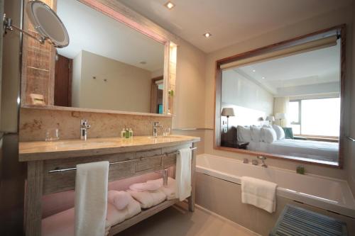La salle de bains est pourvue d'un lavabo, d'une baignoire et d'un miroir. dans l'établissement Arakur Ushuaia Resort & Spa, à Ushuaia