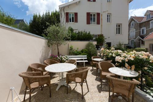 a patio with tables and chairs and flowers at H&ocirc;tel Ma&iuml;tagaria in Biarritz