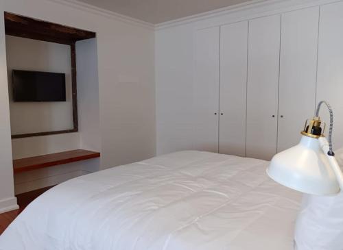 a white bedroom with a white bed and a lamp at Apartamentos Ázera - Laura Ázera in Praia da Vitória