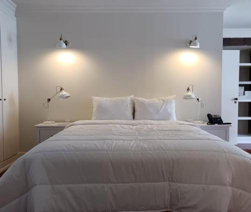 - une chambre avec un grand lit blanc et deux lampes dans l'établissement Apartamentos Ázera - Laura Ázera, à Praia da Vitória