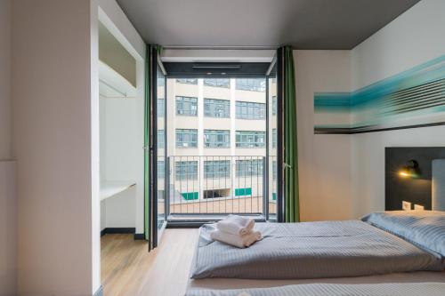 a bedroom with a bed and a large window at Nena Apartments - Kreuzberg 61 in Berlin
