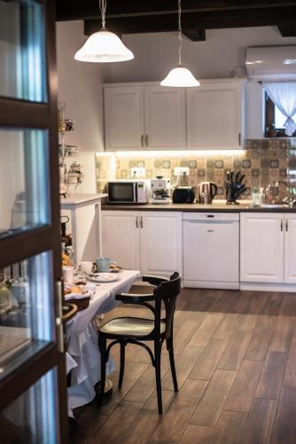 a kitchen with white cabinets and a table and chairs at Boróka Vendégház Tóalmás in Tóalmás
