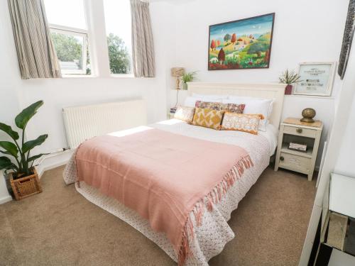 um quarto com uma cama com um cobertor rosa em The Cottage em Penzance