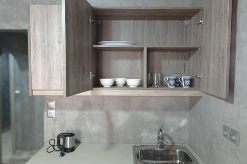 um balcão de cozinha com um lavatório e tigelas numa prateleira em Guest House Pauline em Cidade de Kos