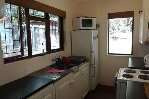 a kitchen with a sink and a microwave at Franskraal-Bit of Salt-Rustic Family Beach House-From R1650 per night, sleeps 6,min 2 nights in Franskraal