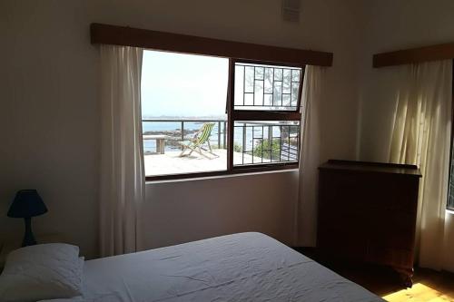 a bedroom with a bed and a window with a view at Franskraal-Bit of Salt-Rustic Family Beach House-From R1650 per night, sleeps 6,min 2 nights in Franskraal