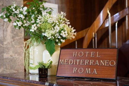 a sign sitting on a table with a vase of flowers at Bettoja Hotel Mediterraneo in Rome