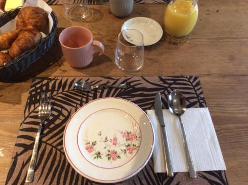 - une table avec une assiette de nourriture et une tasse de jus d'orange dans l'établissement Chambres d'hôtes de charme, à Audouville-la-Hubert