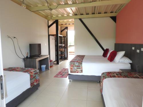 a hotel room with two beds and a tv at Villa Juana Hotel in Pereira