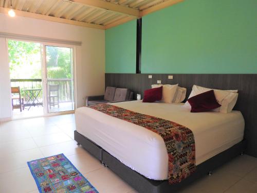 a bedroom with a large bed and a balcony at Villa Juana Hotel in Pereira
