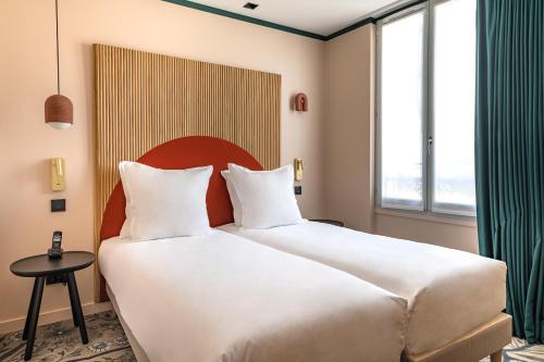 a large white bed in a room with a window at O.Lysée Hotel in Paris