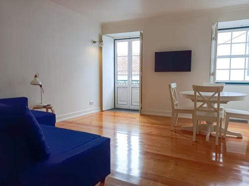a living room with a table and a blue couch at Apartamentos Ázera - Isolino Ázera in Praia da Vitória