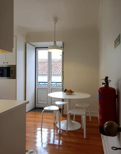 a kitchen with a white table and chairs and a window at Apartamentos Ázera - Isolino Ázera in Praia da Vitória