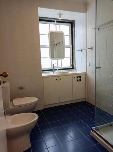 a bathroom with a toilet and a sink and a window at Apartamentos Ázera - Isolino Ázera in Praia da Vitória