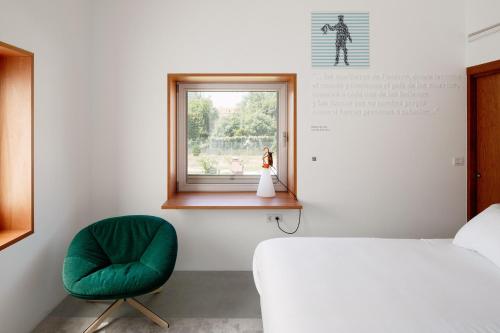 a bedroom with a bed and a green chair at Hotel Bela Fisterra in Finisterre