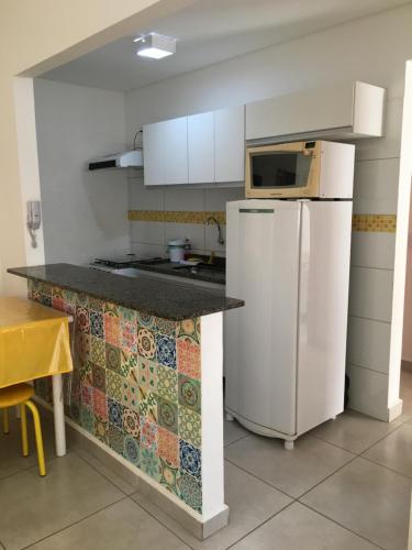 eine Küche mit einem weißen Kühlschrank und einer Mikrowelle in der Unterkunft Apê Amarelo Ubatuba in Ubatuba