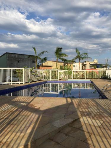einen Pool mit einem weißen Zaun und Palmen in der Unterkunft Apê Amarelo Ubatuba in Ubatuba