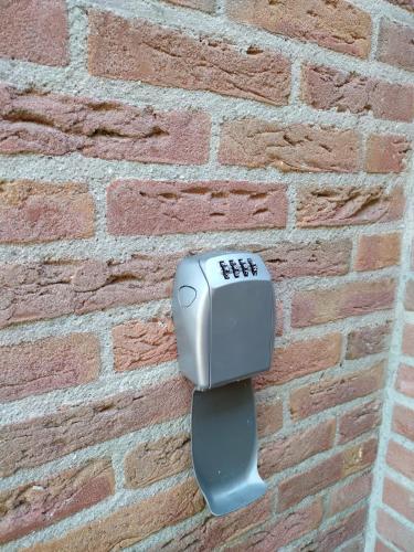a soap dispenser on the side of a brick wall at Vakantiehuis '2bijZee' dicht bij Domburg en strand in Aagtekerke