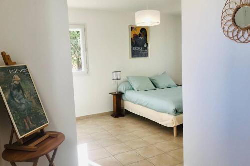 PoggiにあるBel appartement dans villa à la campagne proche d’Ajaccioのベッドルーム1室(ベッド1台、テーブルの絵画付)