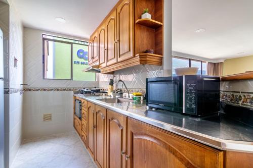 a kitchen with wooden cabinets and a microwave at Alcazar de Oviedo by EE Hoteles in Medellín
