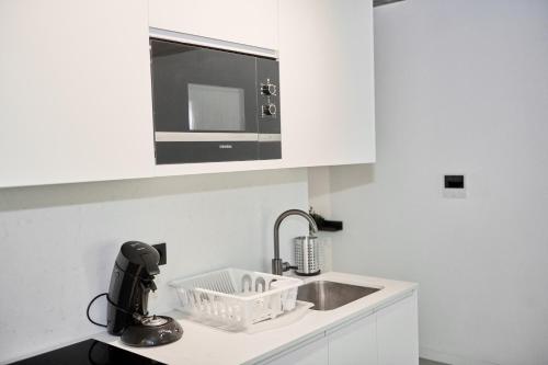 eine weiße Küche mit Spüle und Mikrowelle in der Unterkunft BoLofts in Antwerpen