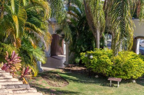 a house with palm trees and a bench in the yard at Pousada Boulevard in Cabo Frio