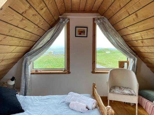 a bedroom with a bed and a chair and a window at Airebroc Byre in Uig