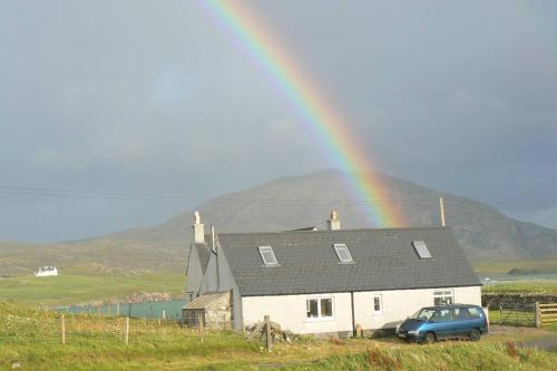 a rainbow over a house with a car parked in front at Airebroc Byre in Uig
