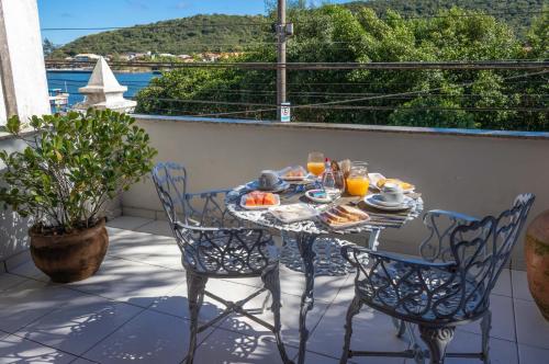 einen Tisch und Stühle auf einem Balkon mit einer Mahlzeit drauf in der Unterkunft Pousada Boulevard in Cabo Frio