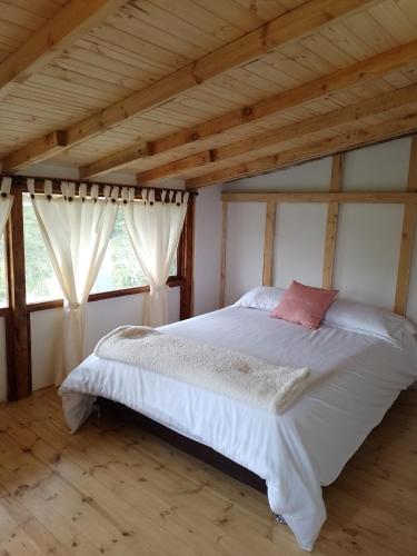a bed in a room with wooden ceilings and windows at La Arboleda in Tilatá