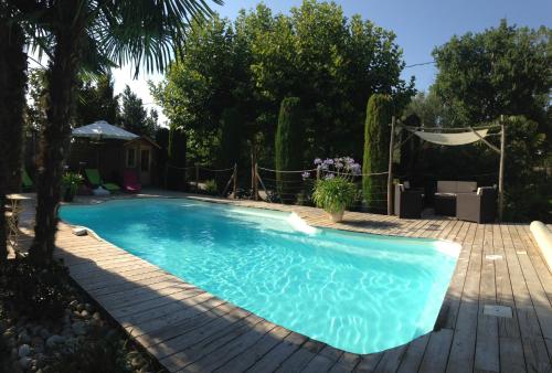 a swimming pool in a yard with a wooden deck at Le Pigeonnier gîte privé climatisé avec piscine couverte et chauffée plus SPA in Alzonne