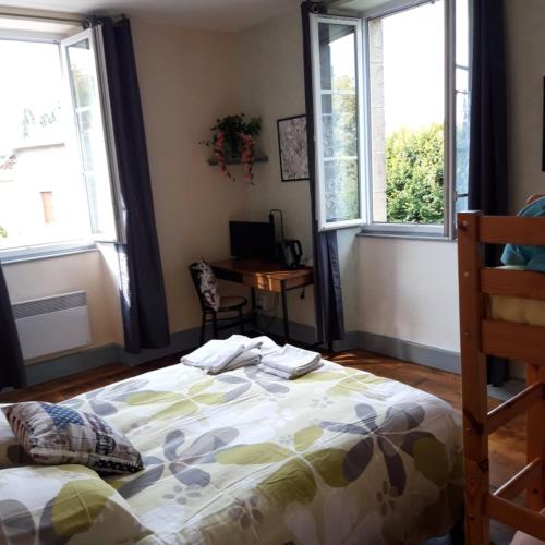 a bedroom with a bed and two windows and a desk at Chambres d'hotes Condat in Condat-sur-Ganaveix