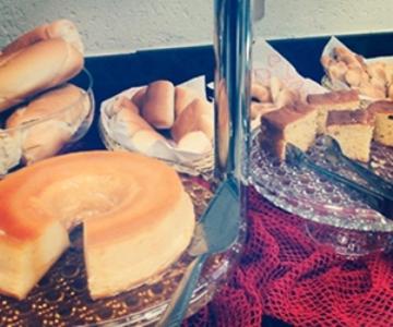 a table with a container of bread and other food at Hotel Domus Itabira in Itabira