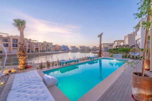 una piscina en un apartamento con palmeras y edificios en La Casa de Playa Tawila on Island 4BR Private with Heated Pool en Hurghada